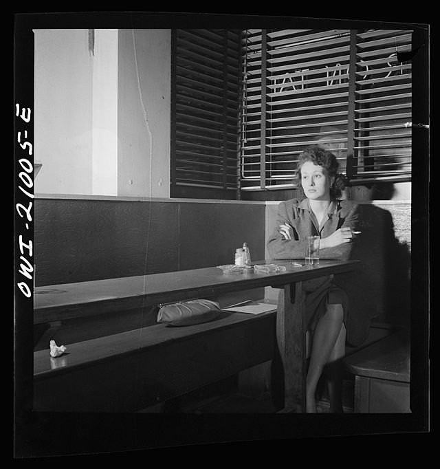 <# Black and white photo of woman sitting alone in a  diner, smoking.#>